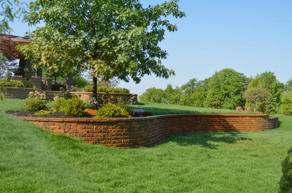 Curved segmental block retaining wall holding a raised lawn and planting bed